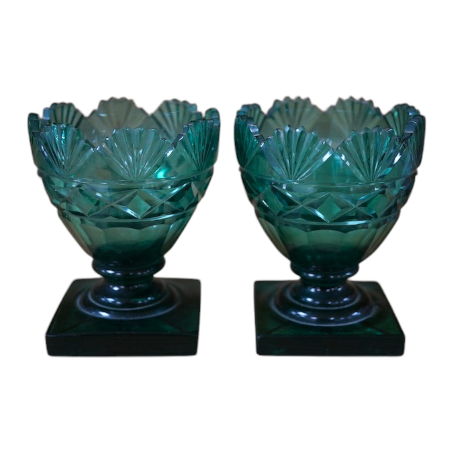 A pair of Regency dark green glass fan cut salts, on square plinths, 9cm. Condition - good, one small chip